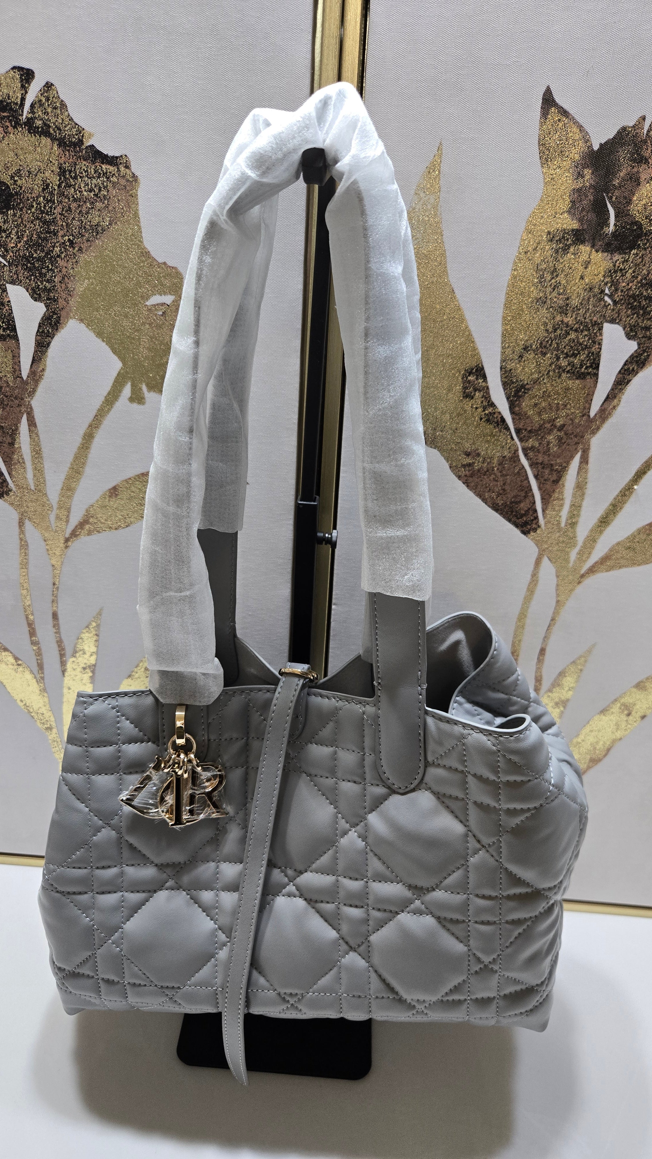 Gray quilted handbag with gold star detail on a decorative surface
