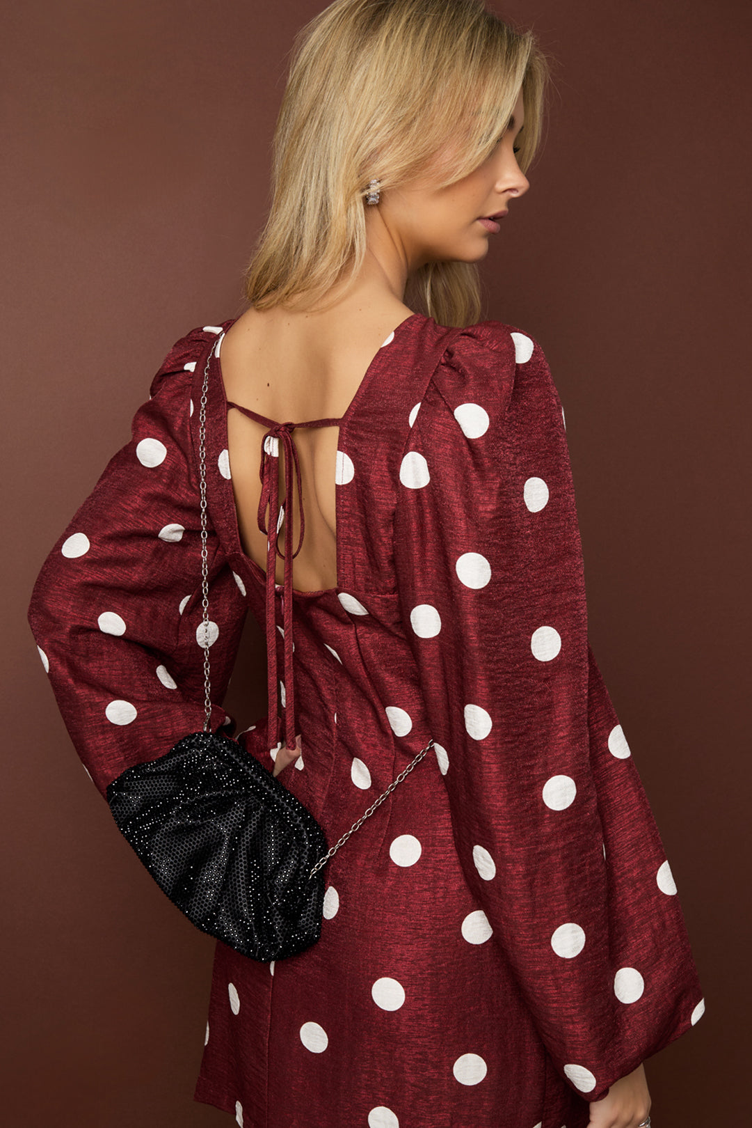 Woman wearing a red dress with white polka dots against a brown background