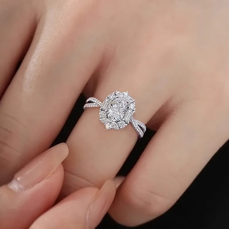 Silver diamond ring on a finger against a neutral background
