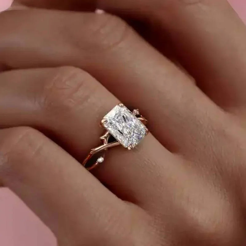 Rose gold ring with a large diamond on a hand against a pink background